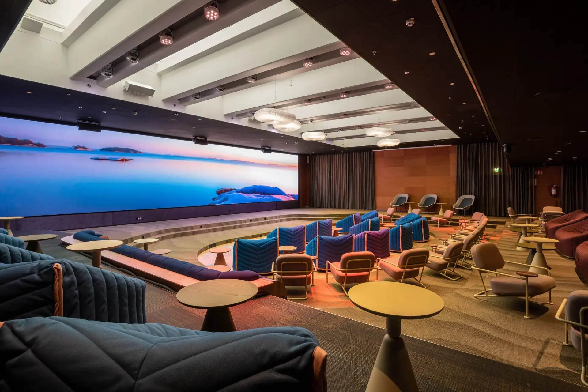 Meeting hall with a wide LED wall, stage and lounge seating