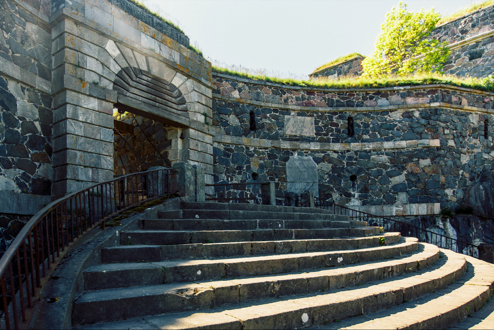 Stone steps curving up to the vaulted King's Gate in the Suomenlinna sea fortress in summer light
