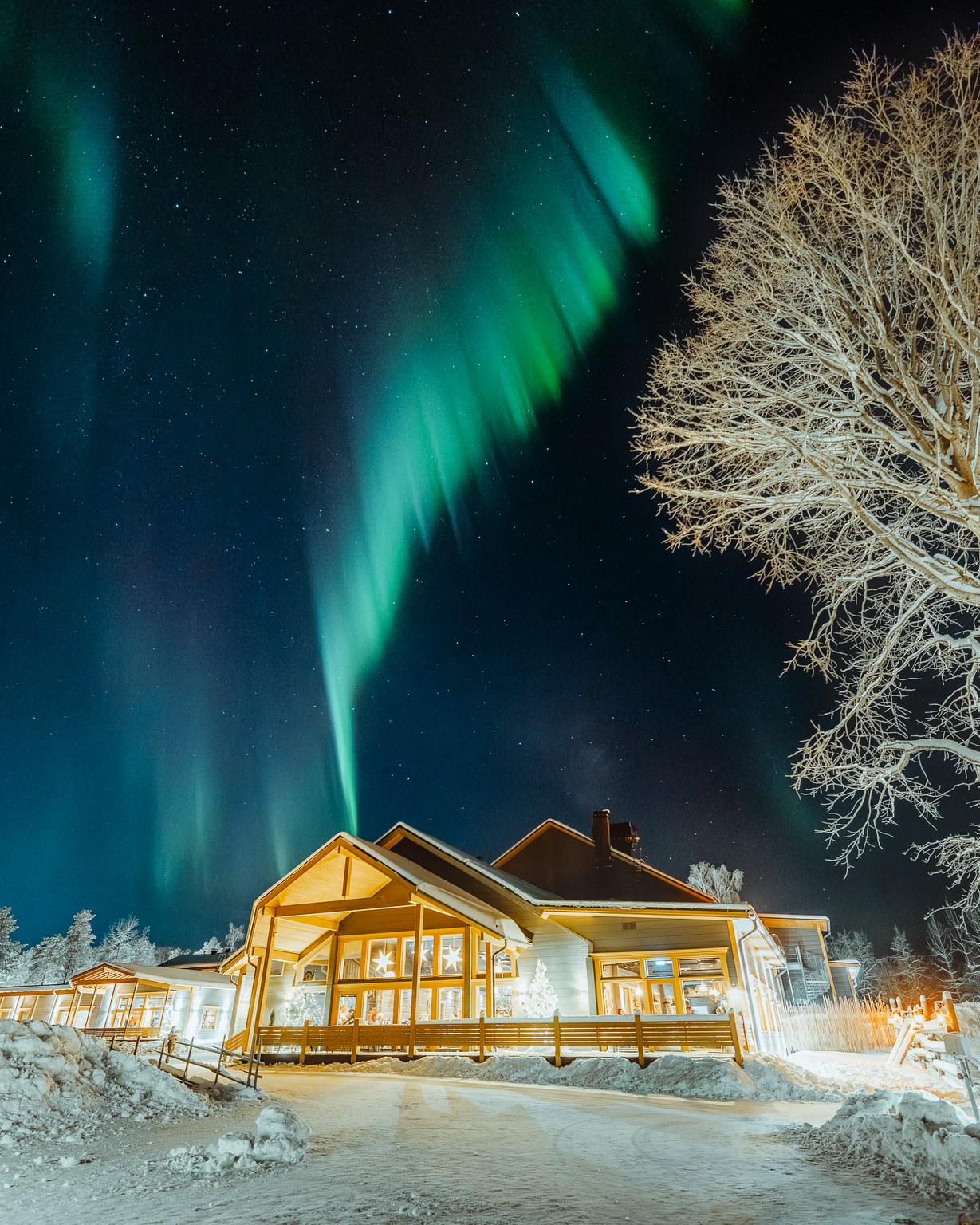 Apukka Resort restaurant lit up at night beneath the northern lights