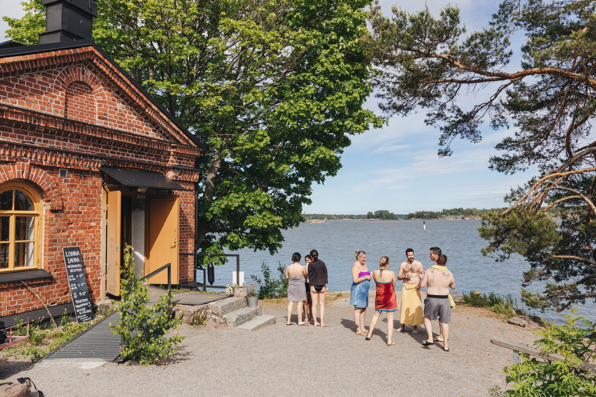 Guests gathered outside the brick island sauna on Lonna with the Helsinki sea behind