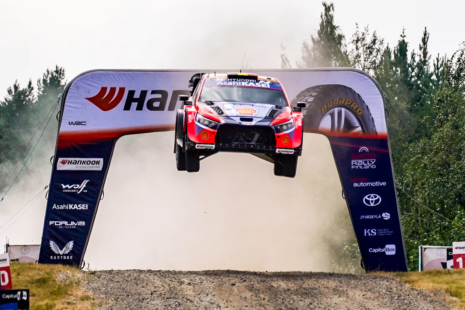 A World Rally Championship car airborne over a gravel crest at Secto Rally Finland in Jyväskylä
