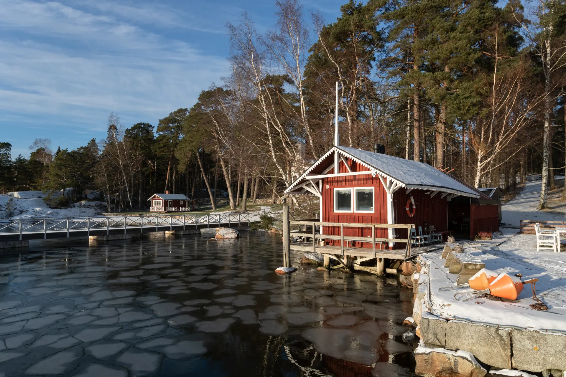 Red wooden sea sauna on a jetty beside ice floes in the Helsinki archipelago