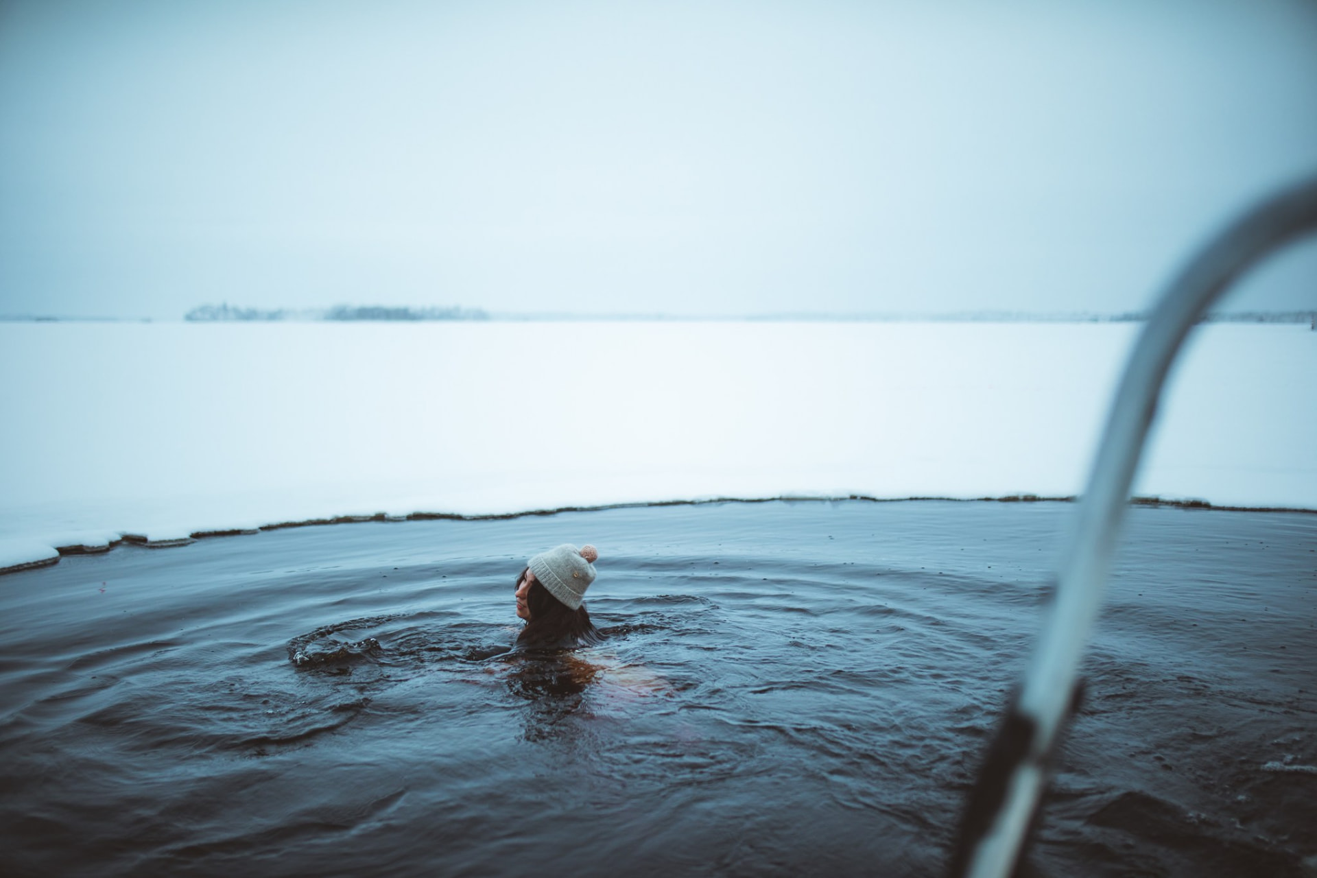 Guest swimming in an ice hole in the frozen lake at Apukka