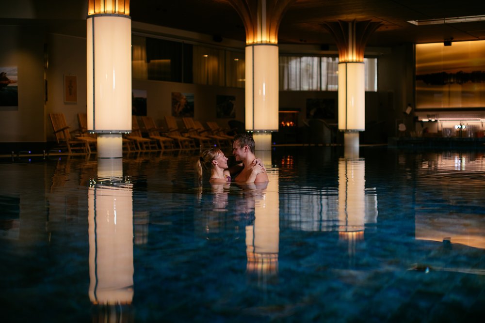 A calm, lantern-lit indoor spa pool with timber columns at an archipelago resort