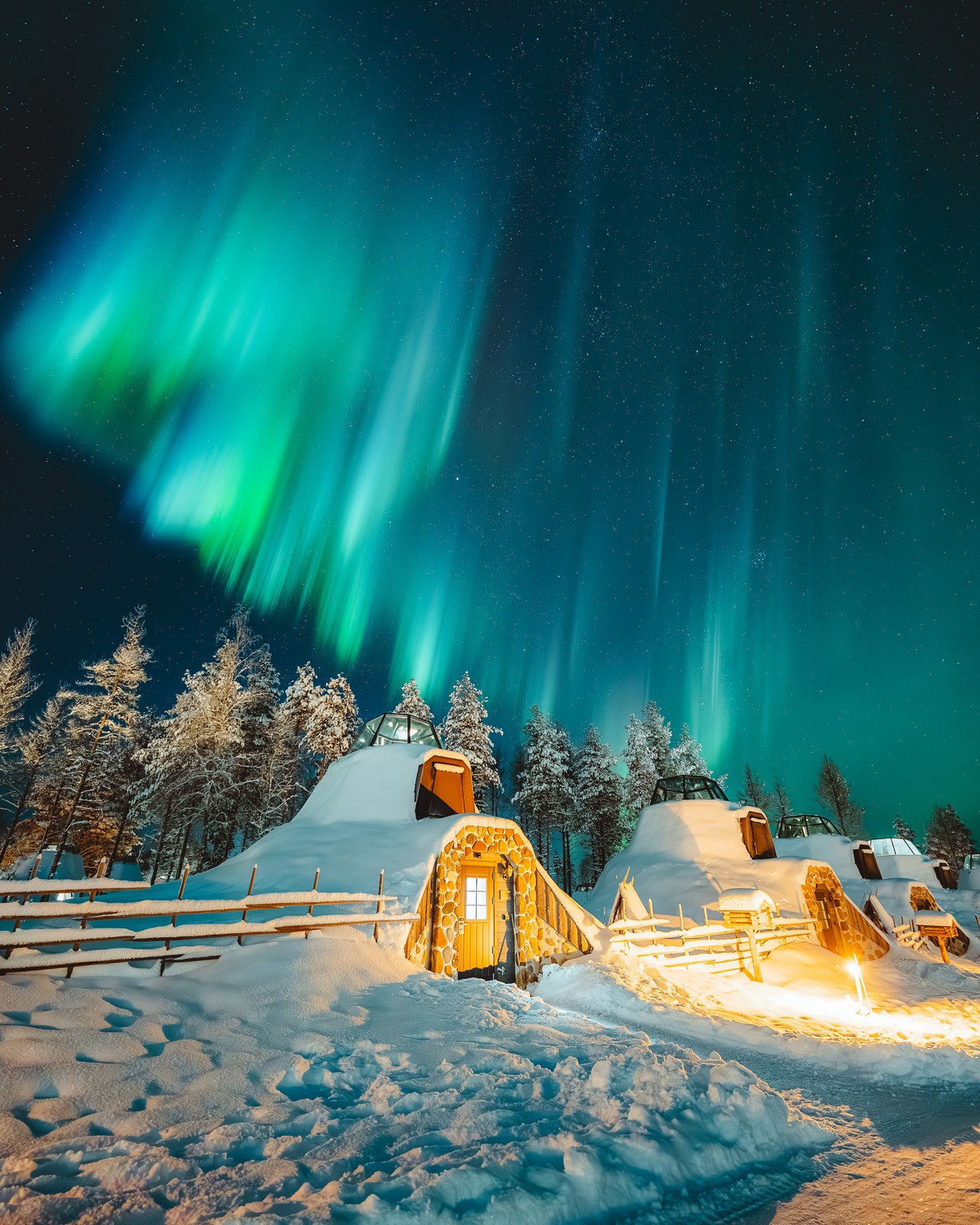 Snow-covered glass igloos at Apukka Resort under the northern lights