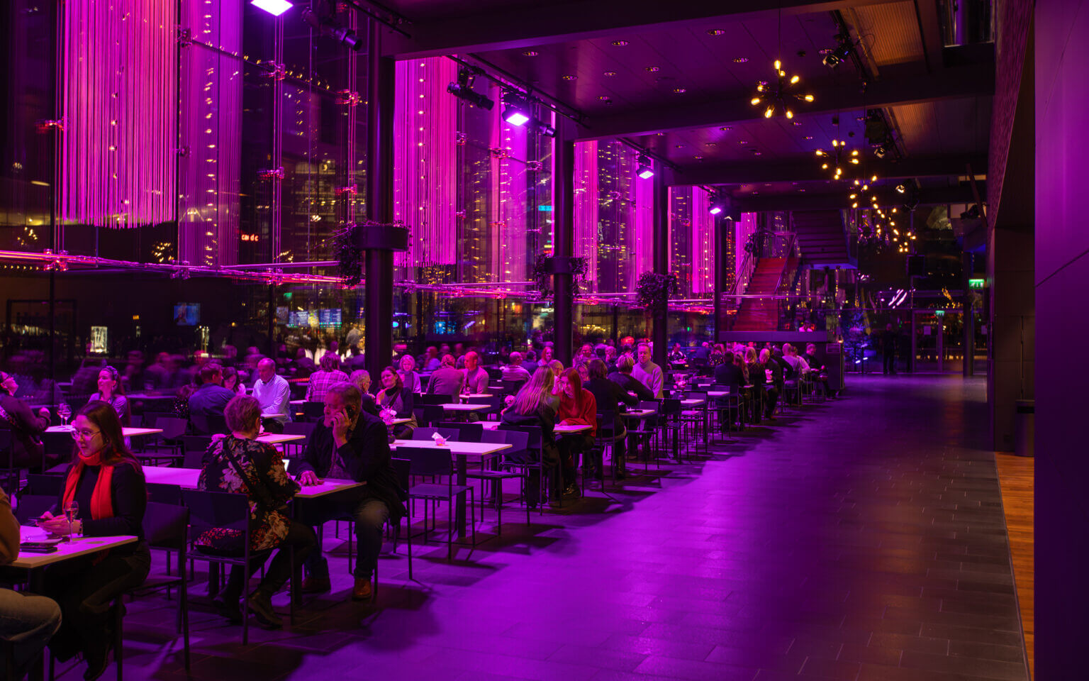 Musiikkitalo foyer at night in violet light with the city glowing outside