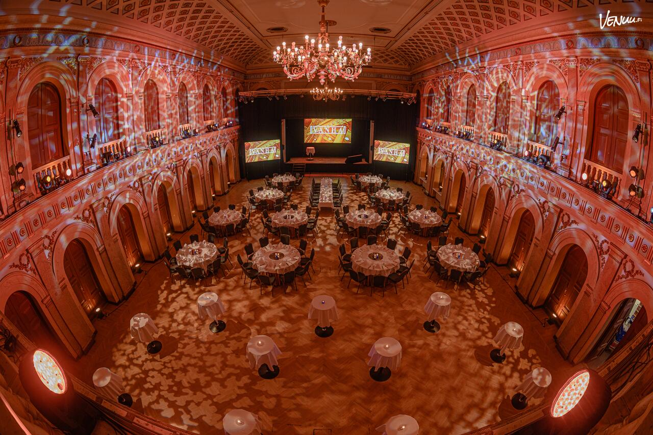 The Old Student House main hall set for a gala dinner with stage and chandeliers